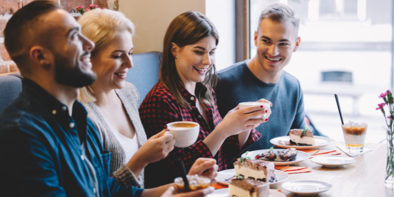 four people sat in a cafe talking drinking coffee